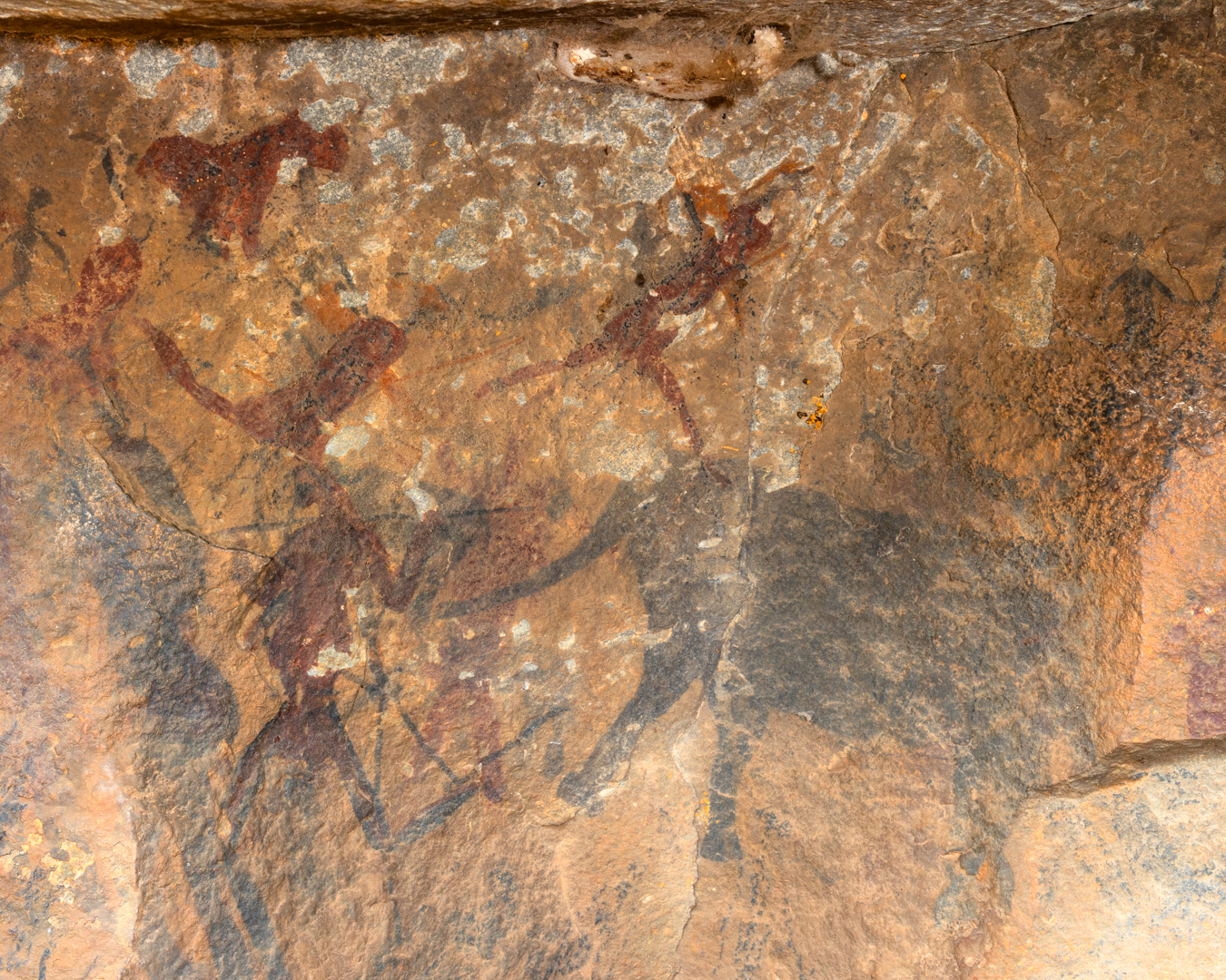 Rock paintings of several running figures and a black elephant